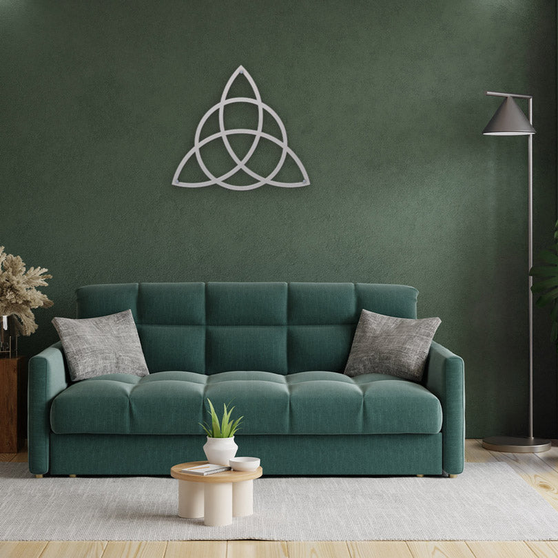 Home Decor Art Wall Sacred Geometry Triquetra Wall Metal Art in silver, is displayed In the center of a modern living room, on a faded green wall, with a green sofa and gray decorative pillows, a Monstera pot and a standing gray lamp.